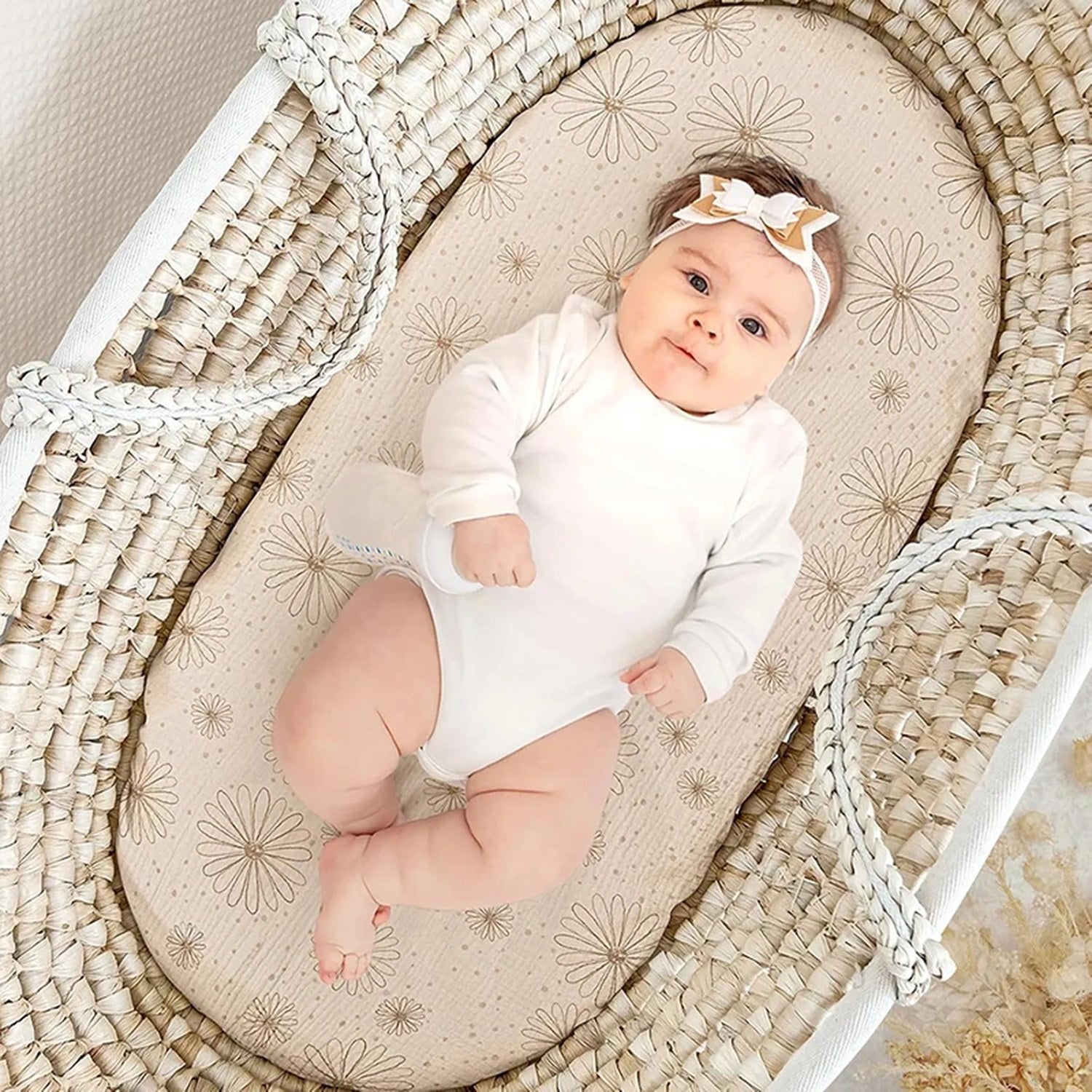 Bébé allongé dans un panier Moïse sur un drap-housse en mousseline à marguerites dorées