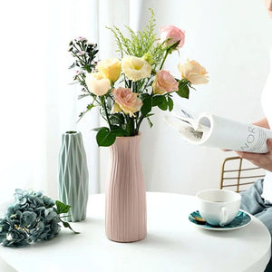 Vase à fleurs origami rose en situation sur une table avec un bouquet de roses