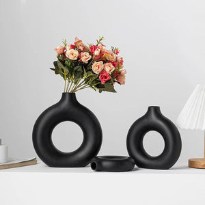 Trois vases anneau noirs de tailles différentes avec un bouquet de roses