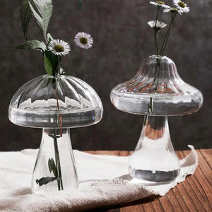 Deux vases champignon en verre avec marguerites sur fond bois naturel