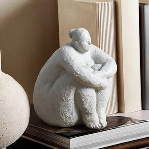 Figurine femme ronde blanche assise sur étagère avec livres et vase