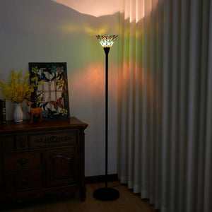 Lampadaire Tiffany vitrail allumé la nuit, reflets colorés projetés sur les rideaux