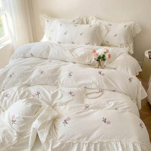 Parure de lit brodée de roses vue d'ensemble dans une chambre lumineuse avec fenêtre