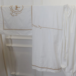 Broderie couronne dorée en gros plan sur la taie de la parure de lit