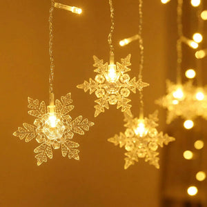 Gros plan sur les flocons de neige LED transparents illuminés en blanc chaud avec bokeh doré