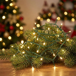 Guirlande lumineuse LED à fil vert allumée en blanc chaud enroulée sur un sapin de Noël dans un salon chaleureux