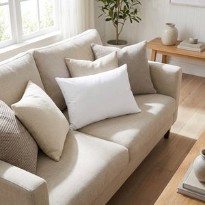 Housse de coussin personnalisée blanche posée sur un canapé dans un salon lumineux