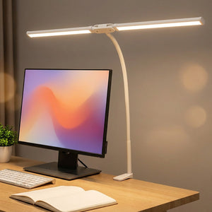 Lampe de bureau LED double tête blanche à pince fixée au bord d'un bureau éclairant un écran