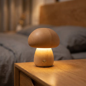 Veilleuse champignon en bois clair allumée posée sur une table de chevet dans une chambre chaleureuse