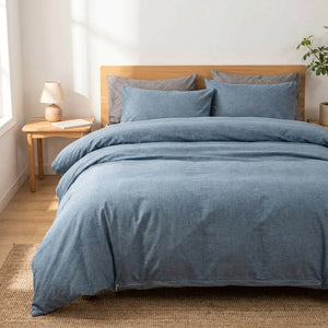 Housse de couette bleue bicolore installée sur un lit fait dans une chambre douce et lumineuse