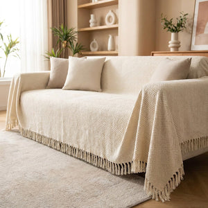 Housse de canapé en chenille blanc crème à franges drapée sur un canapé