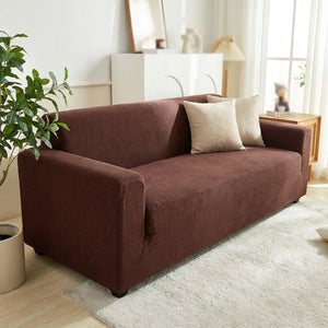 Housse de canapé extensible en jacquard marron installée sur un canapé dans un salon chaleureux