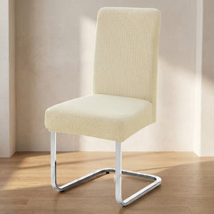 housse de chaise extensible en maille jacquard beige posée sur une chaise dans une salle à manger lumineuse