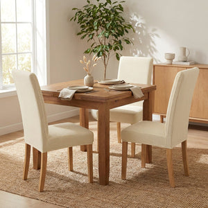 chaises de salle à manger habillées de housses beige autour d'une table dressée