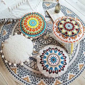 Housses de coussin mandala colorées posées sur un tapis bohème avec un livre et un vase