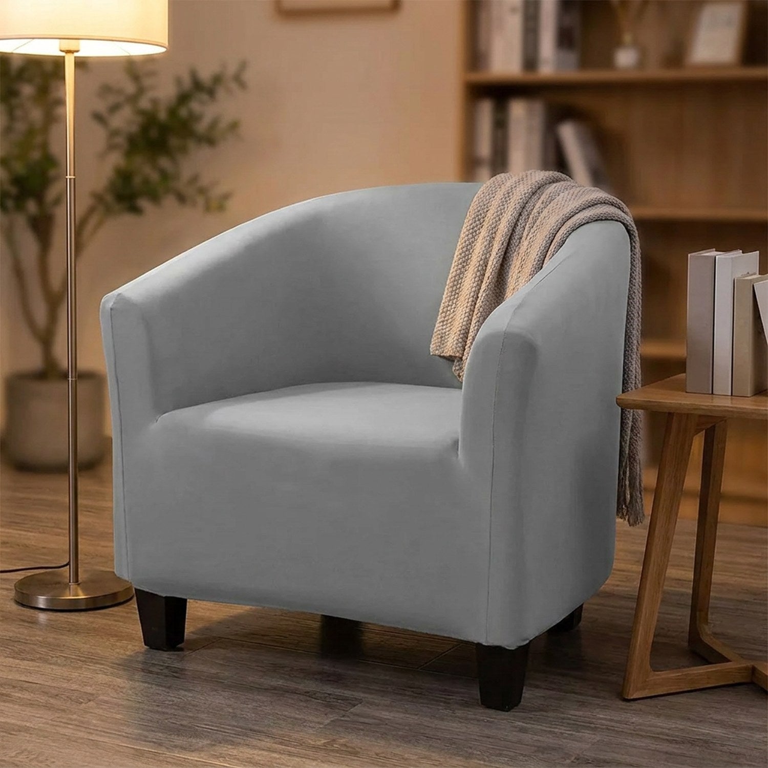 Fauteuil crapaud habillé de sa housse grise dans un coin lecture chaleureux