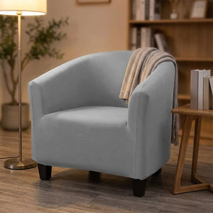 Fauteuil crapaud habillé de sa housse grise dans un coin lecture chaleureux