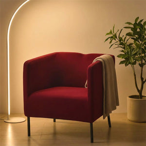 Housse de fauteuil bordeaux sur un fauteuil dans un coin lecture chaleureux