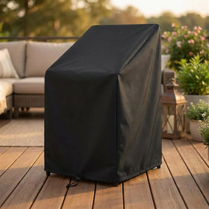Housse de protection noire sur des chaises de jardin empilées sur une terrasse en bois au coucher du soleil