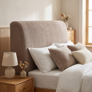 Housse de tête de lit en velours côtelé taupe installée sur un lit dans une chambre lumineuse