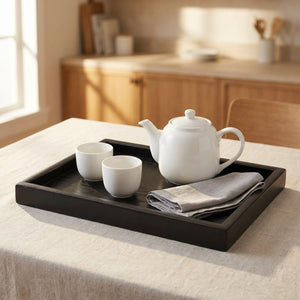 Plateau de service en bois massif noir avec théière blanche et tasses sur table