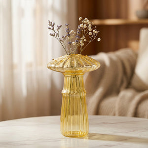 Vase champignon en verre jaune avec fleurs séchées sur une surface en marbre