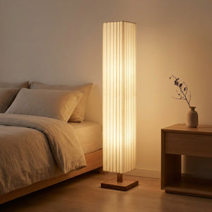 Lampadaire sur pied allumé à côté d'un lit dans une chambre épurée