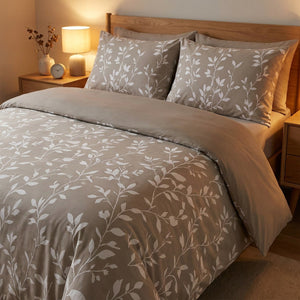 Parure de lit feuillage taupe sur un lit dans une chambre moderne avec lampe de chevet chaleureuse