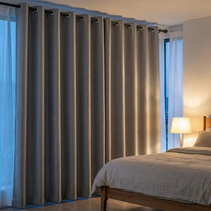 Rideau occultant thermique gris suspendu dans une chambre chaleureuse le soir