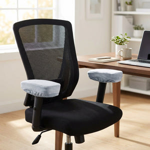Chaise de bureau noire avec deux housses d'accoudoir en velours gris dans un bureau lumineux