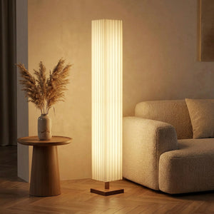 Lampadaire allumé près d'un canapé beige et d'un vase de pampa dans un salon