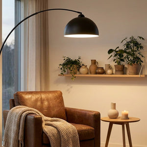 Lampadaire arc LED dans un coin lecture avec fauteuil en cuir et étagère décorative
