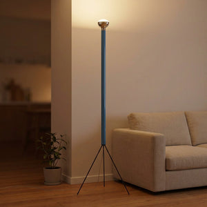 Lampadaire trépied bleu allumé dans un salon chaleureux