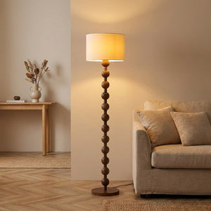 Lampadaire boulier en bois avec abat-jour tissu blanc, style japandi, allumé dans un salon