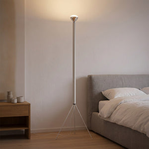 Lampadaire trépied blanc dans une chambre épurée près d'un lit et d'une table de chevet