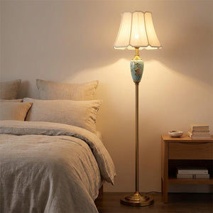 Lampadaire allumé à côté d'un lit dans une chambre chaleureuse