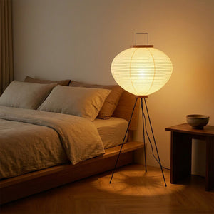 Lampadaire boule papier de riz sur trépied dans une chambre minimaliste près du lit
