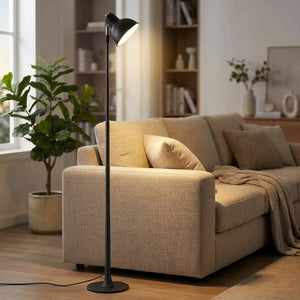 Lampadaire LED noir allumé près d'un canapé dans un salon lumineux