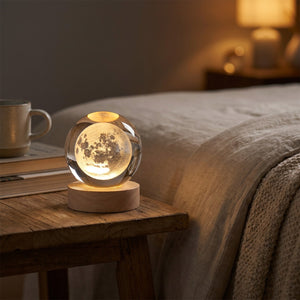 Lampe boule de cristal gravée Lune allumée sur une table de chevet dans une chambre
