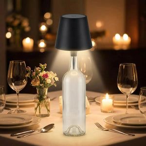 Lampe de table sans fil noire posée sur une bouteille au centre d'une table de dîner aux chandelles