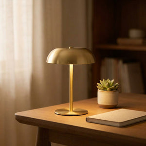 Lampe champignon dorée allumée sur un bureau avec une plante
