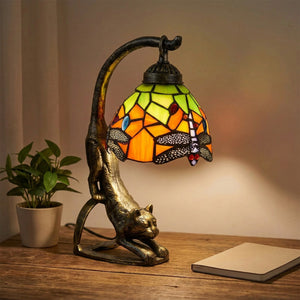 Lampe chat vitrail Tiffany allumée sur un bureau bois avec plante verte