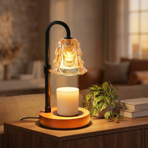 Lampe chauffe-bougie fleur en verre ambré allumée sur une console avec une plante verte et une bougie