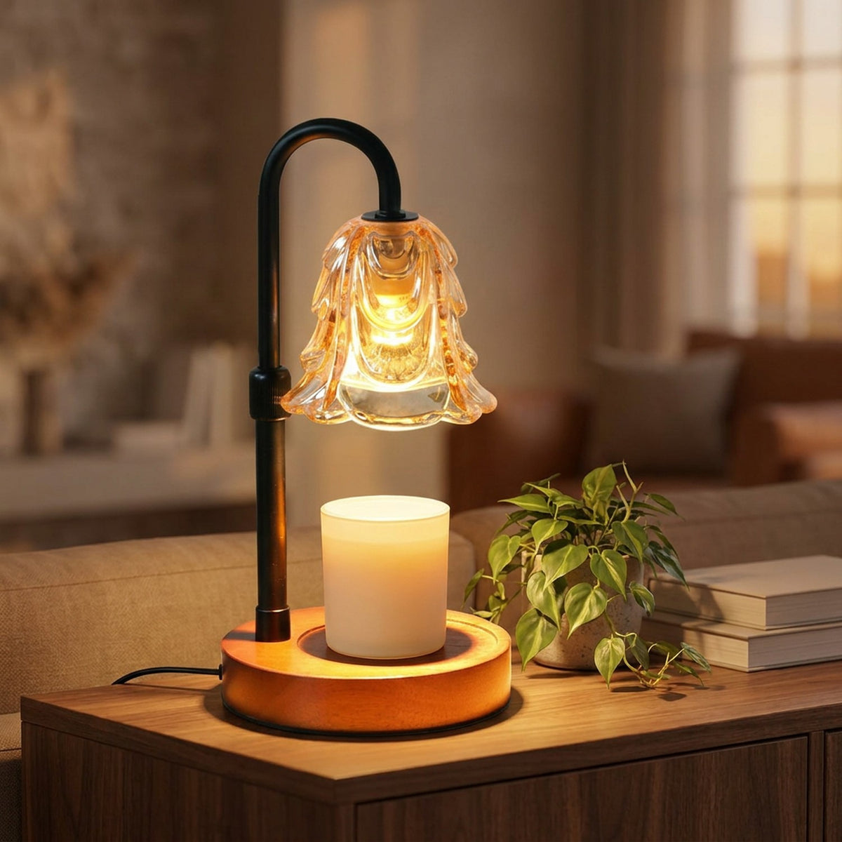 Lampe chauffe-bougie fleur en verre ambré allumée sur une console avec une plante verte et une bougie