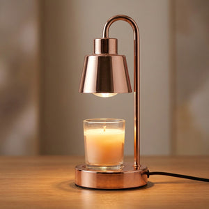 Lampe chauffe-bougie dorée allumée en gros plan avec bougie parfumée