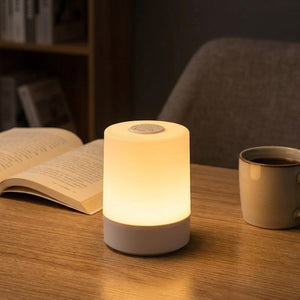 Lampe de chevet allumée sur un bureau en bois à côté d'un livre ouvert