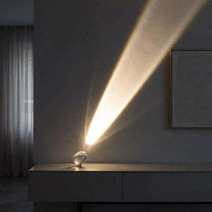 Lampe cristal projetant un halo blanc chaud en forme de comète dans un salon moderne le soir