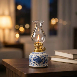 Lampe à huile vintage en céramique fleurie bleue avec flamme allumée sur une table