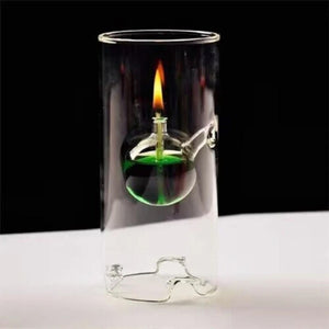 Lampe à huile ouragan en verre transparent avec boule de liquide vert et flamme sur fond sombre