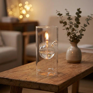 Lampe à huile ouragan en verre transparent avec flamme vivante posée sur une table